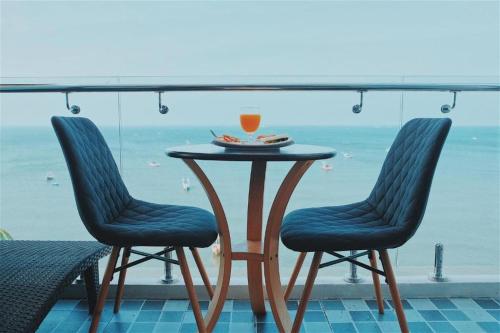 einen Tisch mit zwei Stühlen und einen Drink darauf in der Unterkunft Sea Sand Trees in Bangsaen
