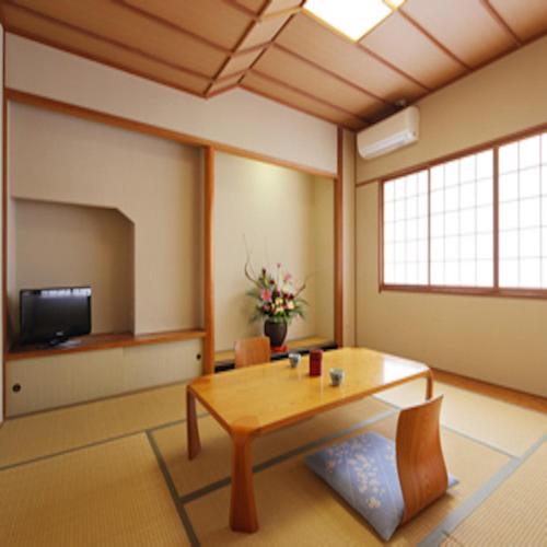 a living room with a table and a tv at Hotel Grand Plaza Urashima in Kurihara