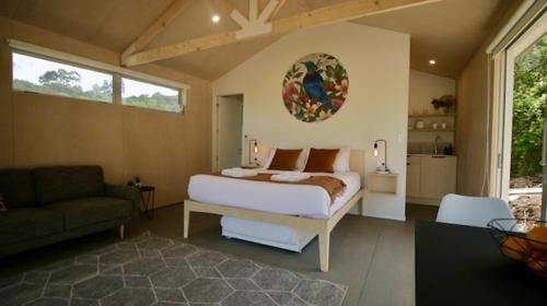 欧尼罗亚One O One Cabins, Waiheke Island的房间里有一张床和一张沙发的卧室