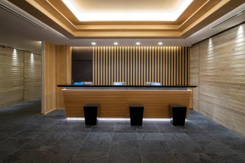 a hotel lobby with a reception desk and benches at JR Clement Inn Kochi in Kochi