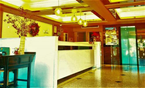 a lobby with a counter and a table with a vase at Gau Shan Ching Hotel in Zhongzheng
