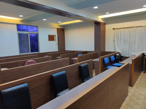 una sala de audiencias con bancos de madera y sillas azules en Bedspace Living, en Udupi