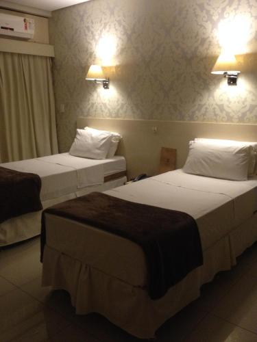 two beds in a hotel room with lights on the wall at Serranos Park Hotel in Paraíso do Tocantins