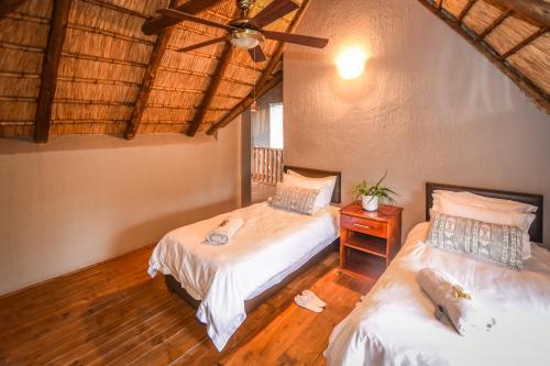 Un dormitorio con dos camas y un ventilador de techo. en Khiza Bush Retreat, en Hoedspruit