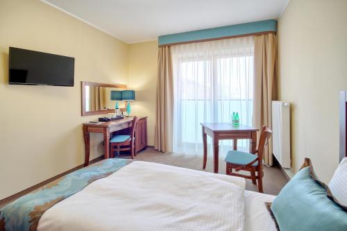 a hotel room with a bed and a table and a desk at Hotel Opole Centrum in Opole