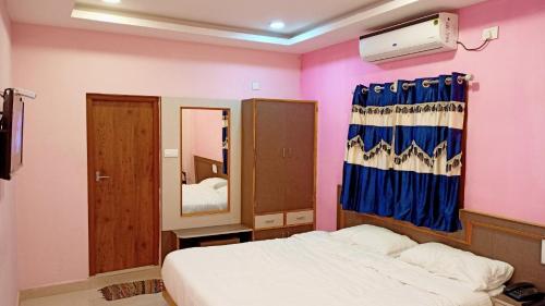 a small bedroom with a bed and a mirror at Aarthi Residency in Kāraikkudi