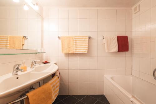 a white bathroom with a sink and a bath tub at An der Via Claudia Augusta in Fiss