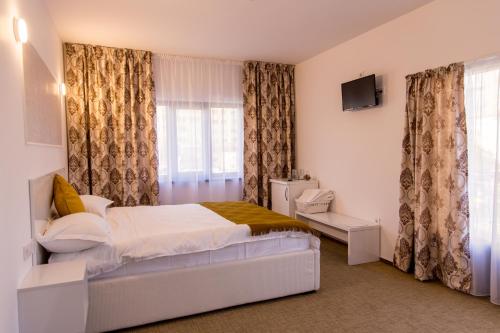 a bedroom with a bed and a television and curtains at Complex Carol in Buzău