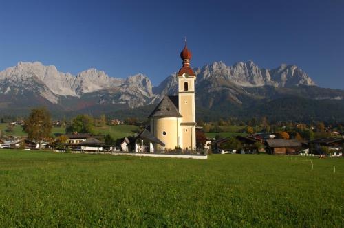 a church in a field with mountains in the background at Gasthof Pension Lanzenhof in Going