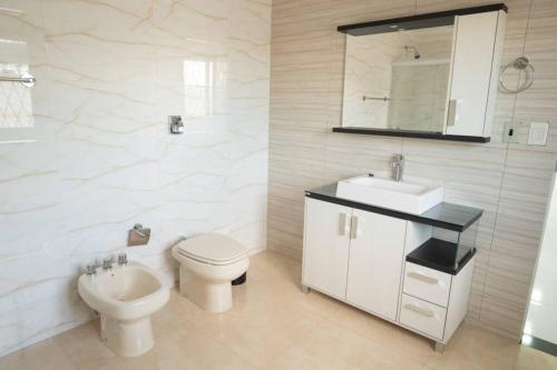 a white bathroom with a toilet and a sink at Apartamento amplio y acogedor en Ciudad del Este in Ciudad del Este