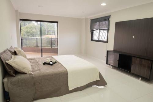 a bedroom with a large bed and a flat screen tv at Apartamento amplio y acogedor en Ciudad del Este in Ciudad del Este
