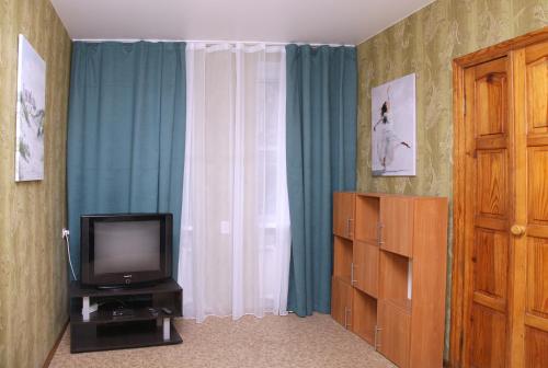 Pokój z telewizorem i oknem z niebieskimi zasłonami w obiekcie Apartments on Yavornitsky av. w mieście Dniepr