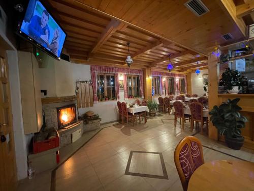 a restaurant with a fireplace and a dining room with tables at Guest House Vila Djokic in Zlatibor