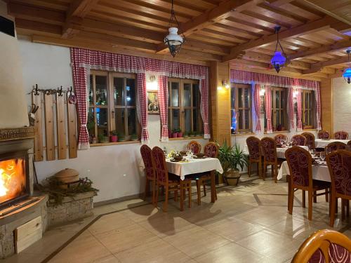 a restaurant with tables and chairs and a fireplace at Guest House Vila Djokic in Zlatibor