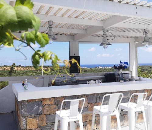 ミラトスにあるMilatos Village Cretan Agrotourism Hotelの白い椅子が備わるバーから海の景色を望めます。