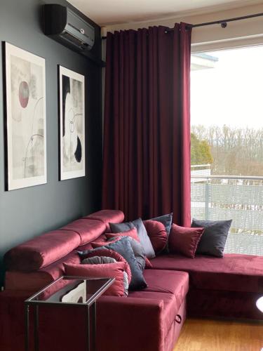 a red couch in a living room with a window at Family & Business Sauna Apartments Klonowa nad Zalewem, Unikat SPA - 2 Bedroom with Private Sauna, Jacuzzi, Air Conditioning, Garage - The Highest Standard! in Kielce