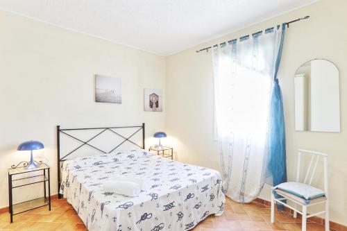 a white bedroom with a bed and a chair at Rosa dei Venti Est in Capoliveri