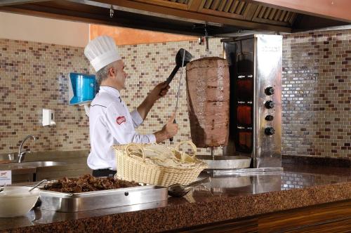 a chef standing in a kitchen preparing food at Belcekiz Beach Club - All Inclusive in Oludeniz