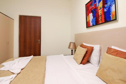 a bedroom with a white bed with a painting on the wall at Apartments in Alley Residence in Yerevan