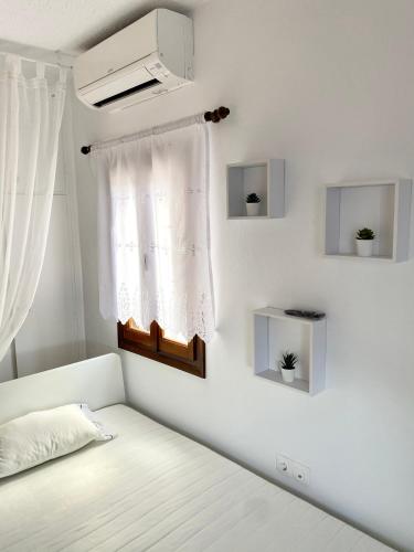a white bedroom with a bed and a window at Lion House I in Ioulida