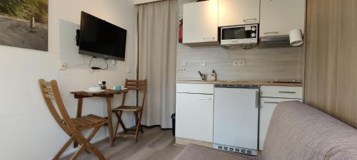 una pequeña cocina con armarios blancos y una mesa pequeña en Nieuw Strand en Petten