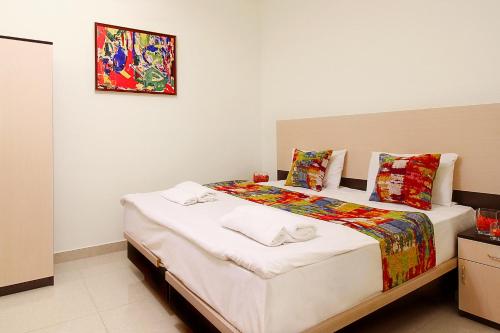 a bedroom with a bed with a painting on the wall at Apartments in Alley Residence in Yerevan