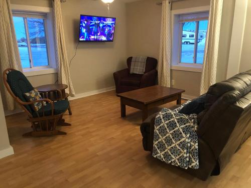 a living room with a couch and chairs and a tv at Burrel Avenue Apartments in Cooperstown