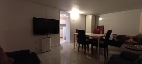 a living room with a table and a television on a wall at 74 Pijnboomstraat in The Hague