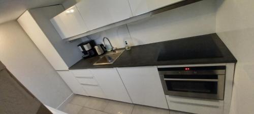 a kitchen with white cabinets and a sink and a stove at 74 Pijnboomstraat in The Hague
