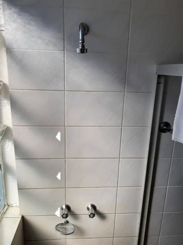 a bathroom with a shower with white tiles at Rede Andrade Guaíra in Curitiba