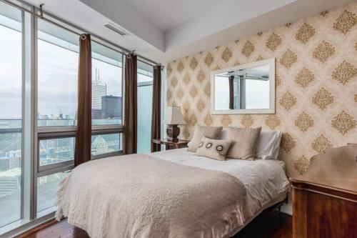a bedroom with a large bed with a window at Two BD CN Tower and Lake Ontario View in Toronto