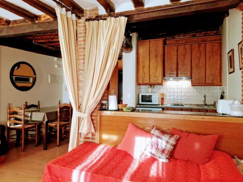 a living room with a red couch and a kitchen at Apartamentos Rurales La Lancha in Aldeanueva de la Vera