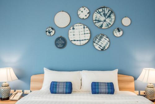 芭達雅中心的住宿－DeeProm Pattaya Hotel，一间卧室,墙上有蓝色的墙壁和盘子