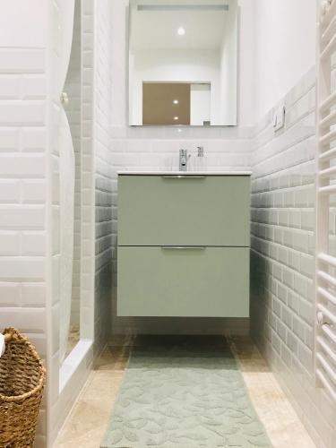 une salle de bain blanche avec un lavabo et un miroir dans l'établissement Cocon douillet face à la mer de Cagnes sur mer, à Cagnes-sur-Mer