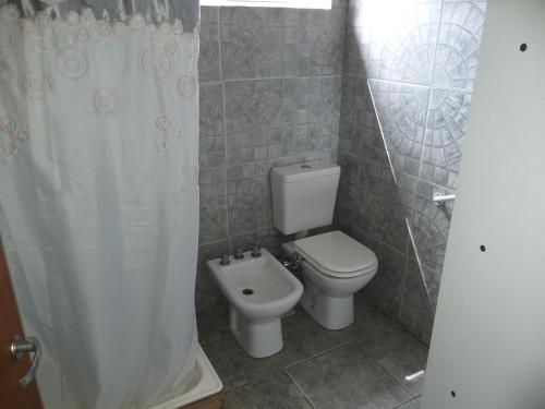 a bathroom with a toilet and a shower curtain at Las Lechuzas in Tandil