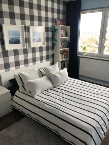 ein Schlafzimmer mit einem gestreiften Bett und einem Fenster in der Unterkunft Apartament White glove Kołobrzeska in Danzig