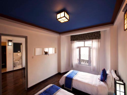 a bedroom with two beds and a blue ceiling at Shambaling Boutique Hotel in Kathmandu