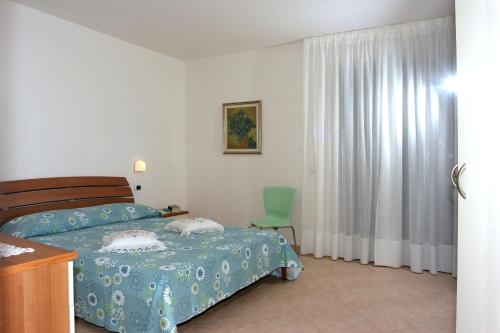 a bedroom with a bed and a green chair at Verde Mare "Appartamenti per Vacanze" in Tortoreto Lido