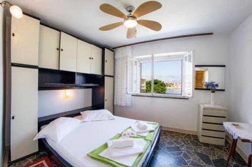 a bedroom with a bed with a ceiling fan and a window at Beachfront house Pope B&B in Selca