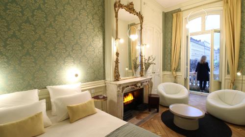 a bedroom with a bed and a fireplace and a mirror at MiHotel Bellecour in Lyon