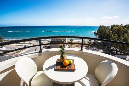 a table and chairs on a balcony with a view of the ocean at Pigeon Beach Hotel Apartments in Limassol