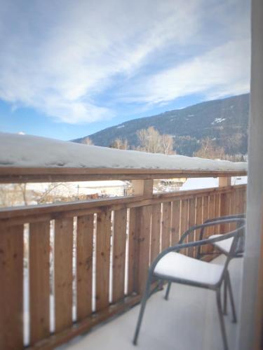 a chair sitting on a deck with a snow covered mountain at Gasthof Auwirt in Sankt Michael im Lungau