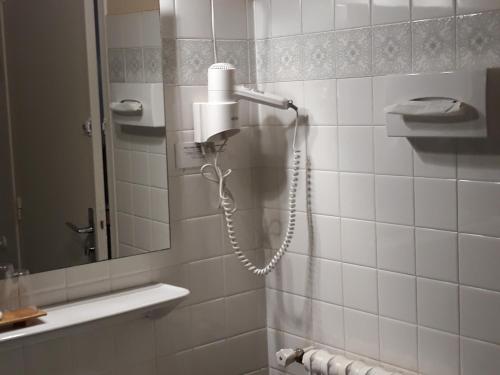 een douche met een föhn in de badkamer bij Hôtel Ambroise in Uzerche