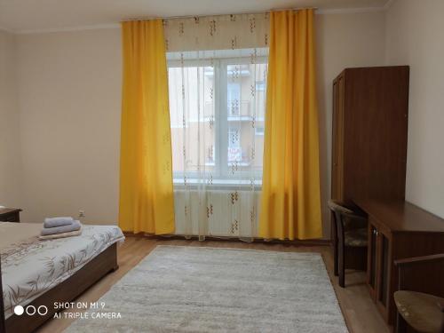 a bedroom with yellow curtains and a large window at Apartments "Domovik" Івана Парканія 2а кв 19 in Mukacheve