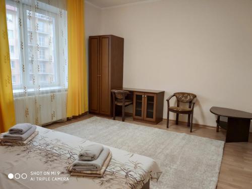 a bedroom with a bed and a table and a window at Apartments "Domovik" Івана Парканія 2а кв 19 in Mukacheve