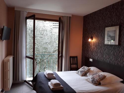 a hotel room with a bed and a large window at Hôtel Ambroise in Uzerche