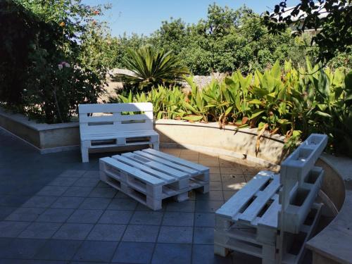 two white benches sitting on top of a patio at Casa Sbrizza in Rosolini