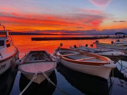 a group of boats sitting in the water at sunset at Apartments Adriatic 3 in Selce