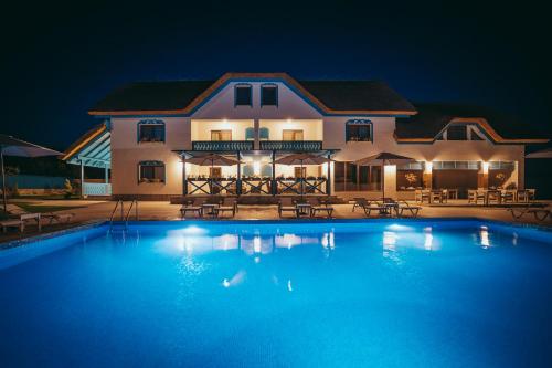 a large swimming pool in front of a house at night at Pensiunea Briza Marii Jurilovca in Jurilovca