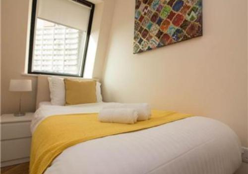 a bedroom with a bed with a yellow blanket and a window at StayZo Serviced Accommodation 16 Premier Lodge in Southampton